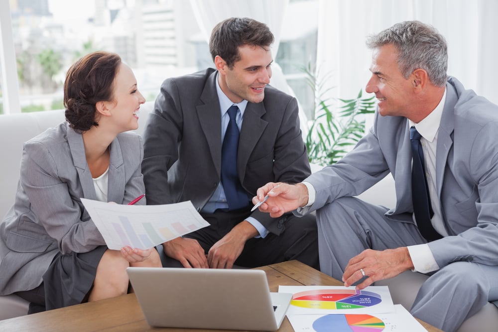 Cheerful business people analyzing financial graphs of their company in cosy meeting room Cheerful business people analyzing financial graphs of their company in cosy meeting room